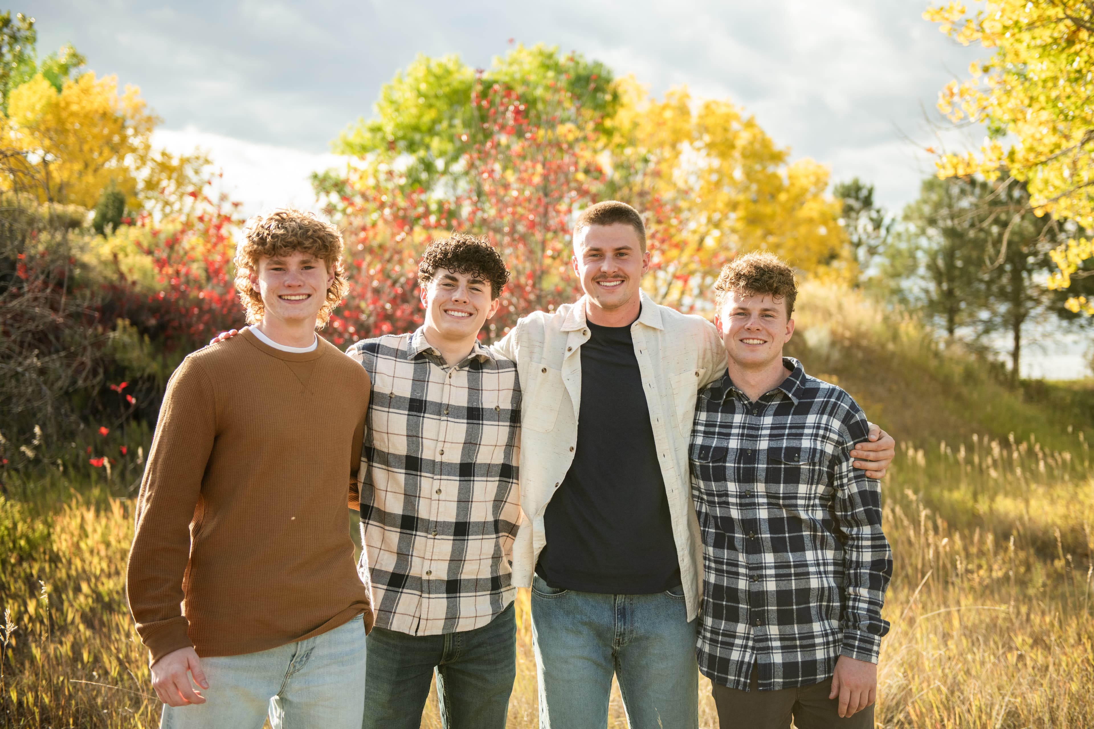 Jackson, Owen, Max, and Gavin Morgenegg smiling outdoors in a golden autumn field